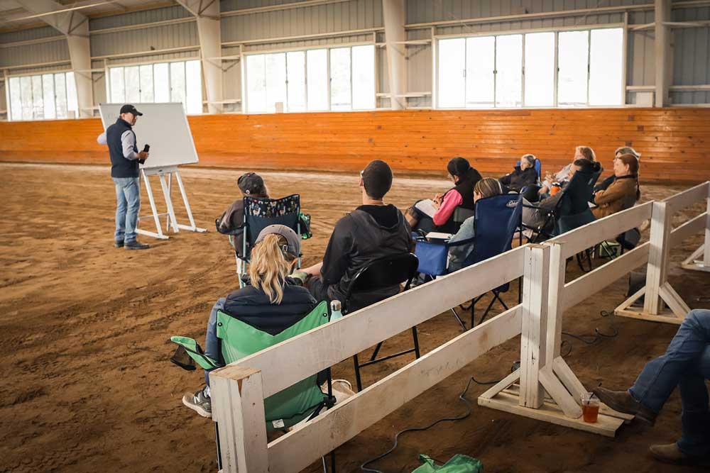 Man at whiteboard in horse stable teaching a class.